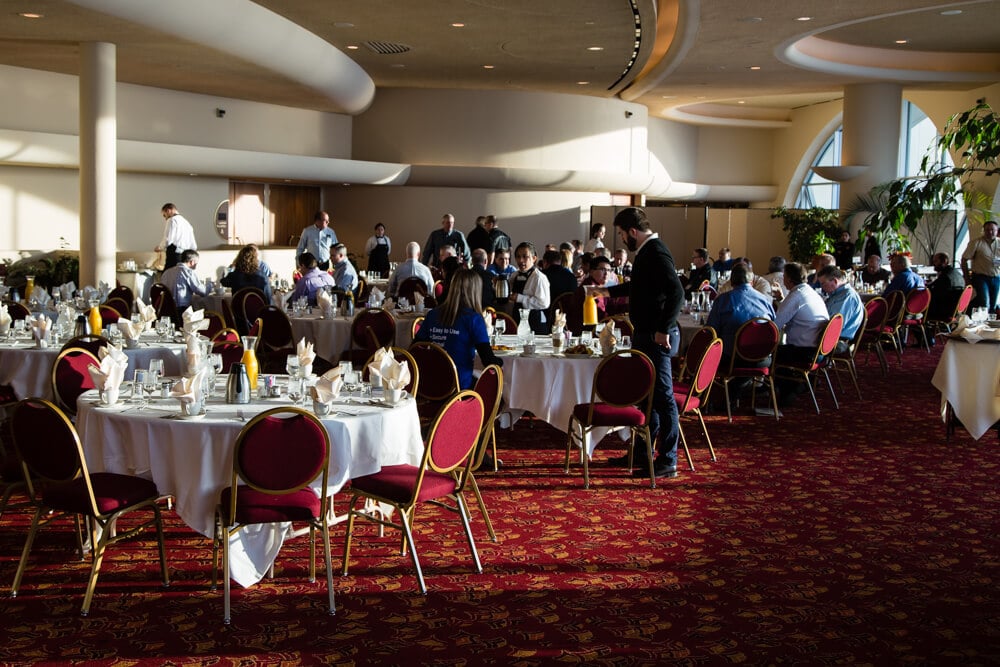 People gathered around round tables having breakfast at an event