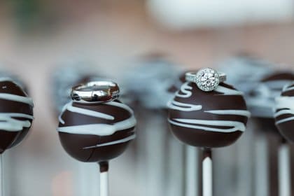 J-+-E-Vendor-0082 A close-up photo of chocolate cake pops with engagement rings on top of them.