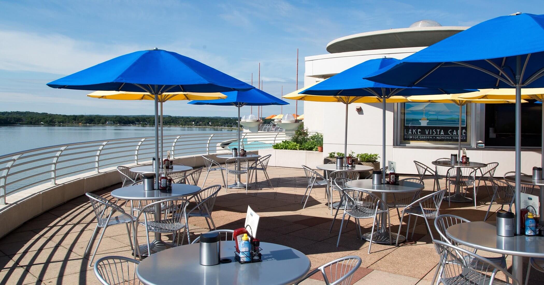 LakeVistaCafe Empty tables at Lake Vista Cafe with a view of the lake with yellow and blue umbrella canopies