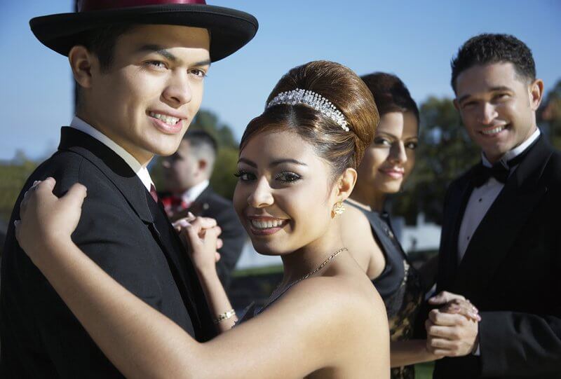 Quinceanera Two Latin American couples in formal outfits posing for camera, dancing and celebrating Quinceanera, a guy in the background