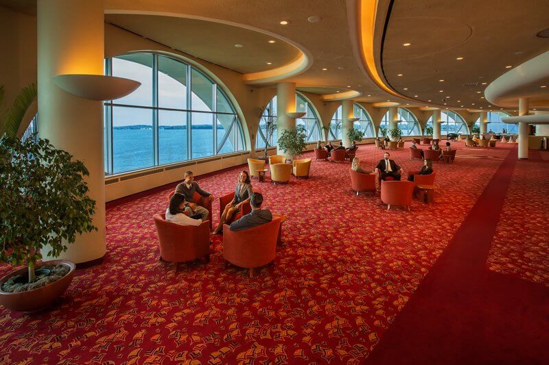 Monona Terrace spacious lounge with views of the lake and different groups of people sitting in different areas of the lounge