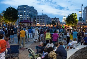 A large group of people at a rooftop concert talking and having fun