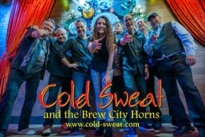 A smiling band with nine members poses energetically in front of red curtains and illuminated instruments. Text reads "Cold Sweat and the Brew City Horns."