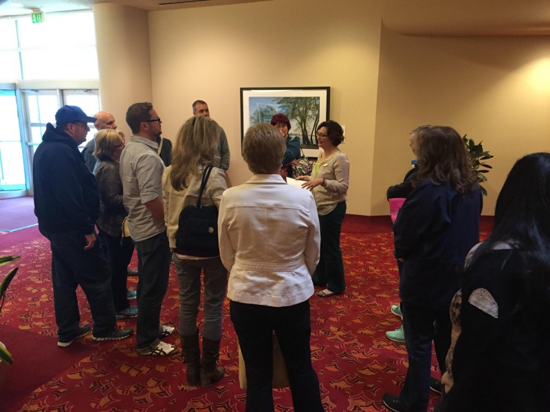 A woman talking to a group of people gathered around a painting