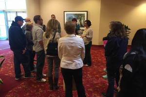 A woman talking to a group of people gathered around a painting