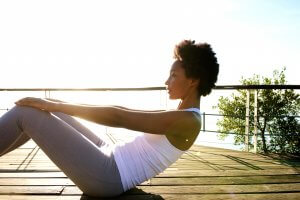 Side portrait of healthy young woman doing stomach crunches near the beach