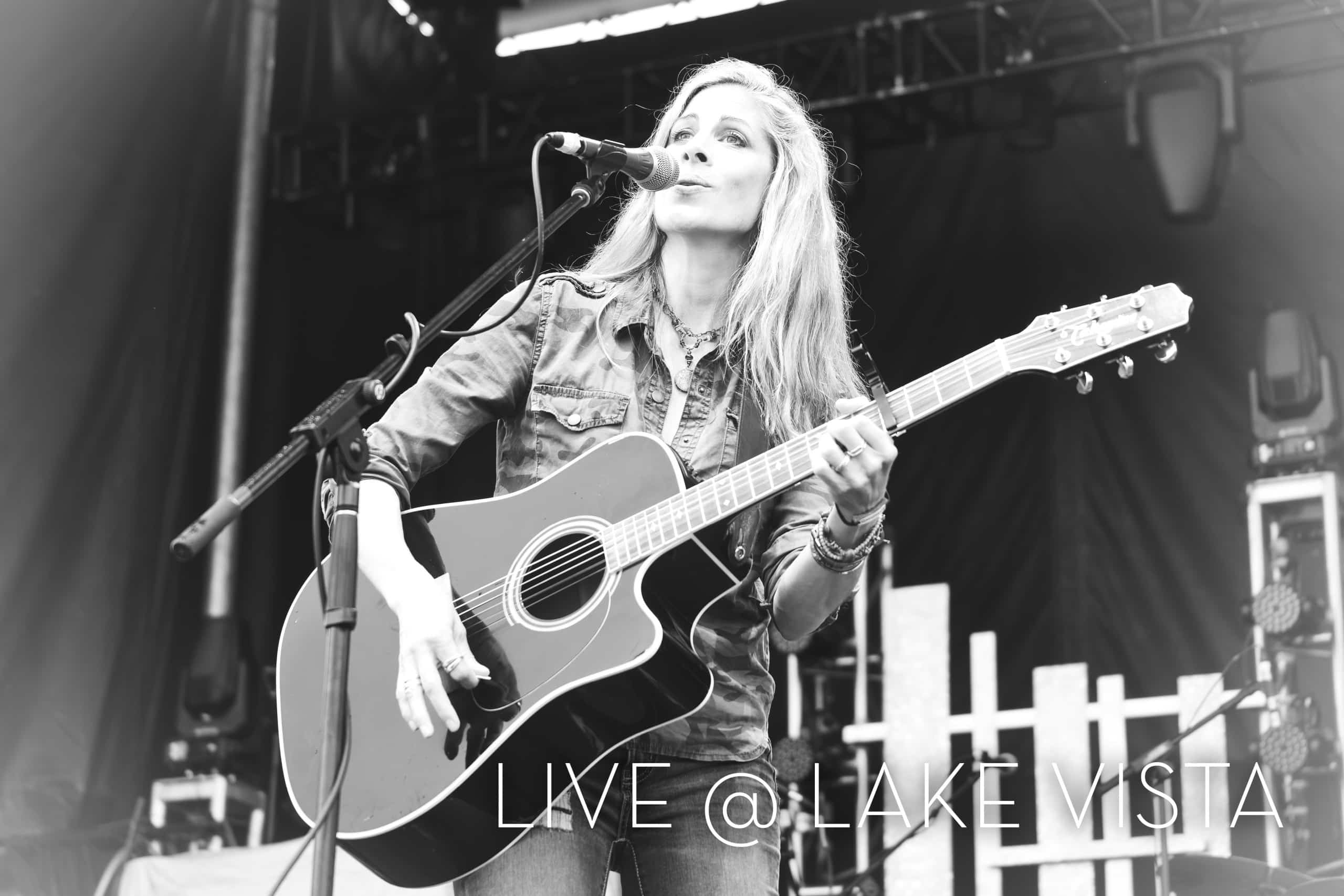 Beth Kille performs live outdoor with guitar and microphone.
