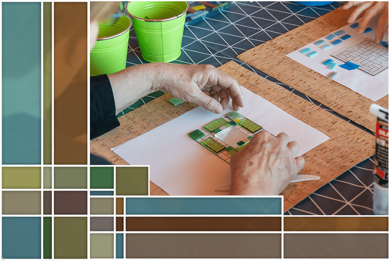 Two adults work on stained glass art in the style of Frank Lloyd Wright geometric stained glass.