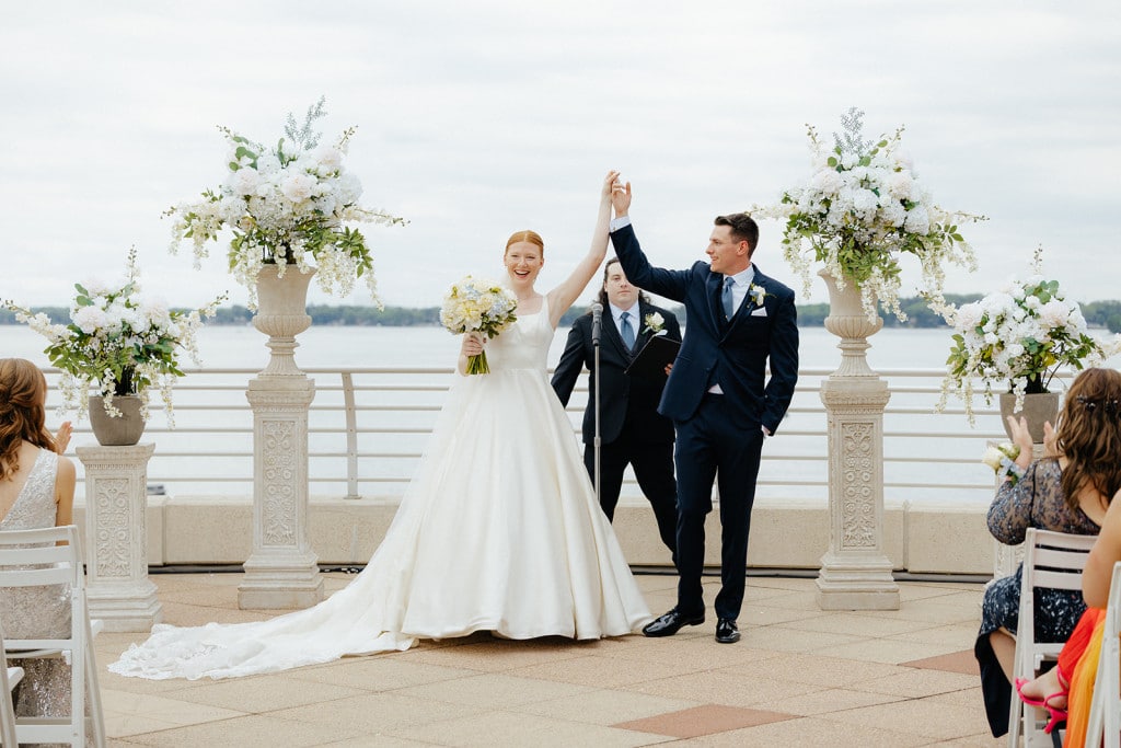 A man and woman present themselves for the first time as a married couple in front of their guests at their Monona Terrace rooftop wedding.